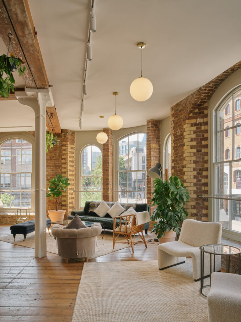 Stylish loft lounge with large arched windows, modern sofas, and indoor plants in London