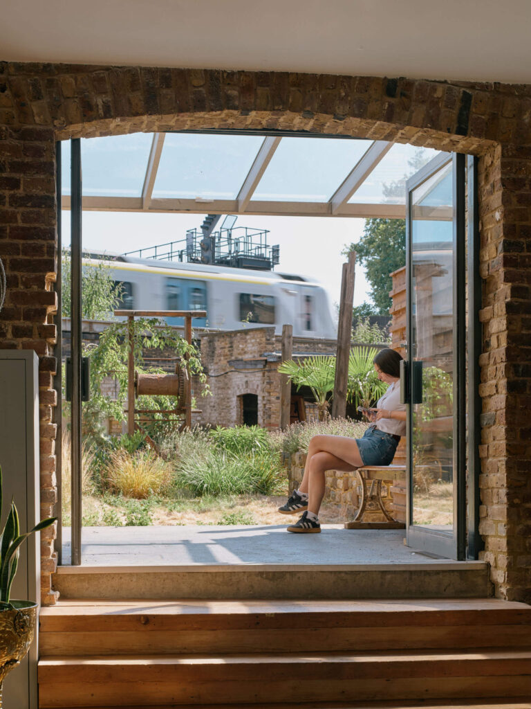 Arched doorway with garden view, train passing, and seating at Menier Venues