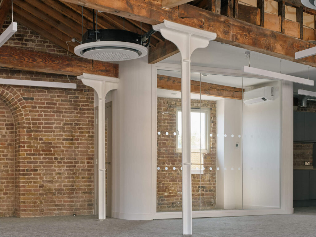 Glass meeting room with brick wall and exposed beams in modern office at Menier