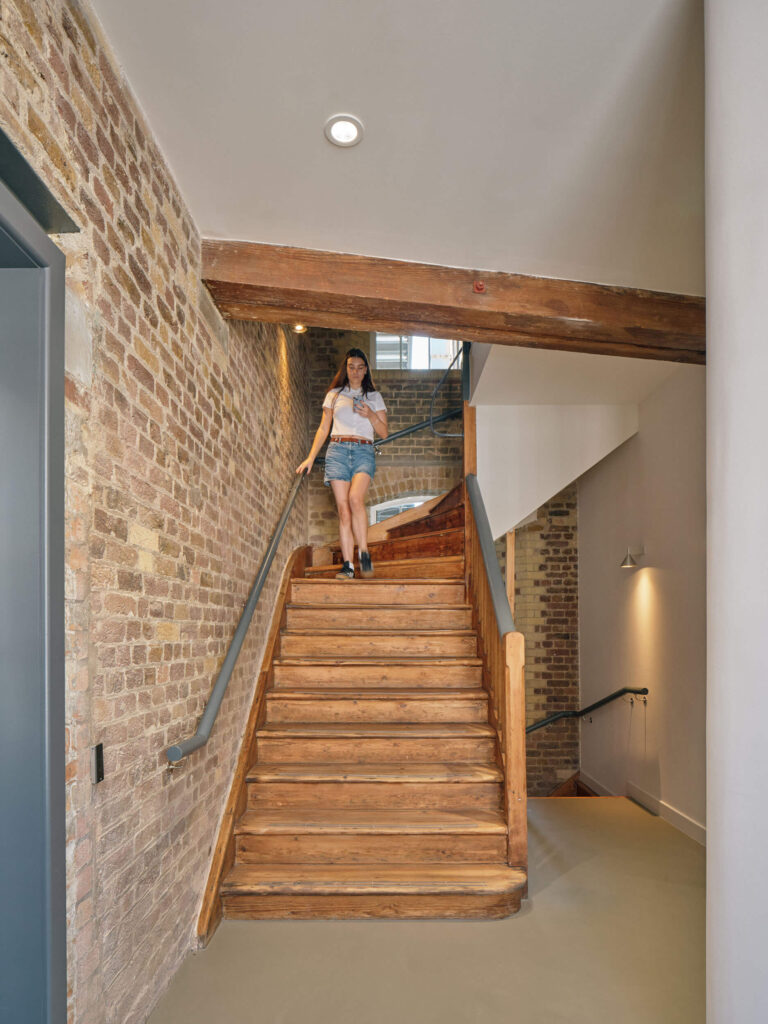 Woman descending heritage staircase with exposed brick at Menier Venues