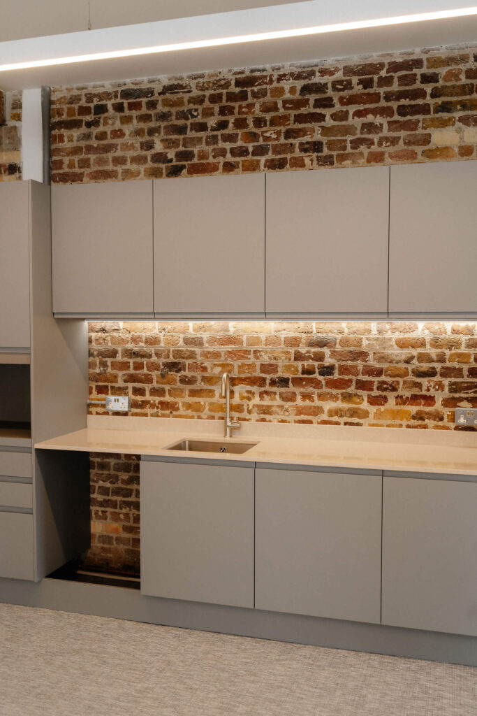 Industrial kitchenette with exposed brick and modern grey units