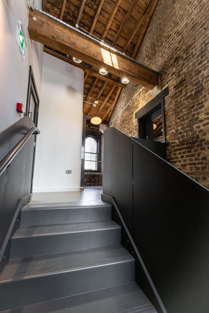 Industrial office staircase with brick wall and timber ceiling