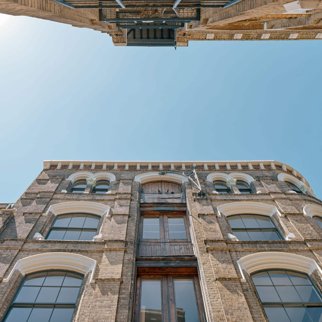 Upward facade view of the Menier Building with arched windows in London