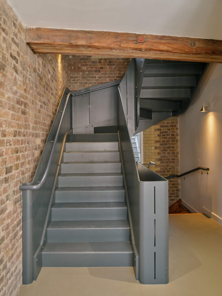 Modern metal staircase with exposed brick in industrial office at Menier