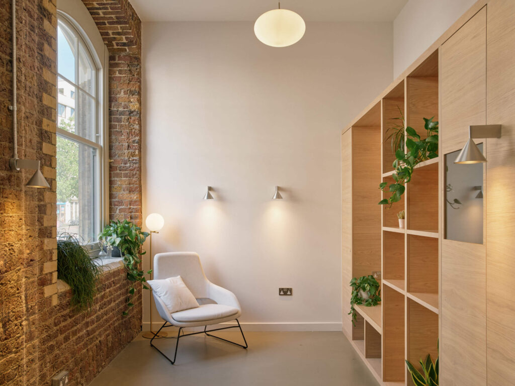 Relaxation corner in office with brick wall, armchair, and plant display at Menier