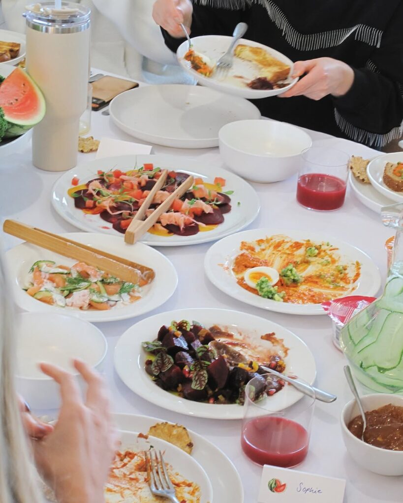 Dining table topped with fresh beetroot, salmon, and juice spreads served during a healthy breakfast event.
